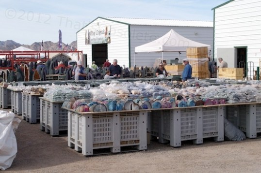 Some tables with cut stones and bags of pebbles, with some large geodes further back.