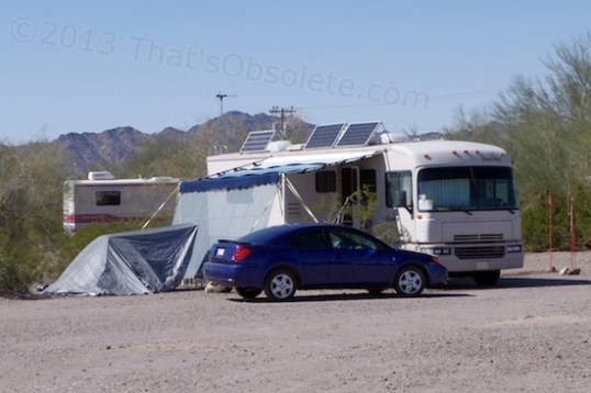 With and awning out and partition blocking the low sun, these folks are comfy. The tarp on the left is simply shielding equipment from the sun. They even have bird feeders staked in to the ground!?! I think they've been doing this awhile.