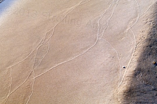 Each wave leaves a sand trail at its edge.