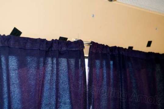 The side curtains are held top and bottom by baling wire linked to small brackets screwed into the plastic trim. The goal is to limit the cascade of cold air coming from the glass.