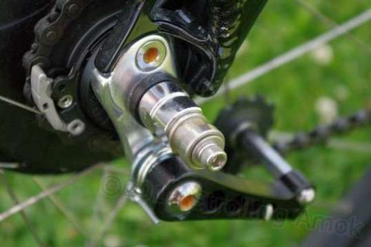 "10x1 BOB's Nutz" replace the stock nuts that lock the axle in place. A stainless steel bobbin near the outer end supports the trailer arm.