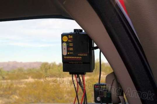 A Batteryminder SCC-180 solar controller is attached to the truck's rear window with adhesive-backed Velcro. The little box below is Batteryminder's version of a voltage meter.
