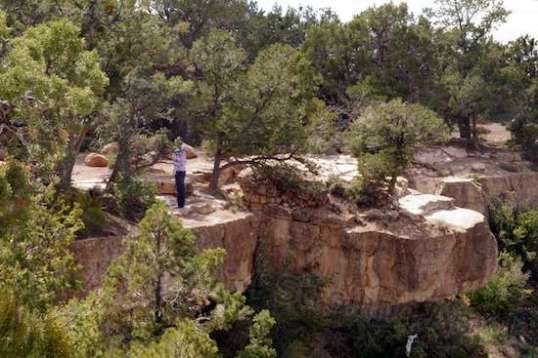 Just left is a guy posing near the ledge to have his picture taken.
