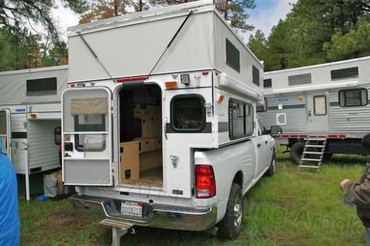 This is called a truck camper, made by Four Wheel. Sparse in features, lightweight and built to survive off-road pounding and bed flex, it's been continually honed since the 70s. 