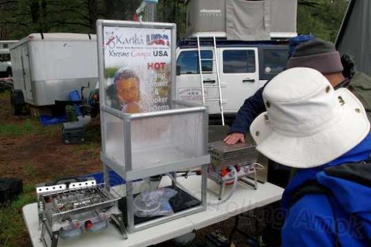 Got no water heater? Don't want to wait for a solar bag to warm all day? This propane water heater heats on the fly, and the one on the left does that and cooks, too. The South African lady I talked to hoped that this KaribaProducts.co.za design was about to be picked up by trailer maker Campa USA. A 12VDC pump pulls water from the hose in a bucket, jug or stream, through the heater and hosed showerhead, and onto you.