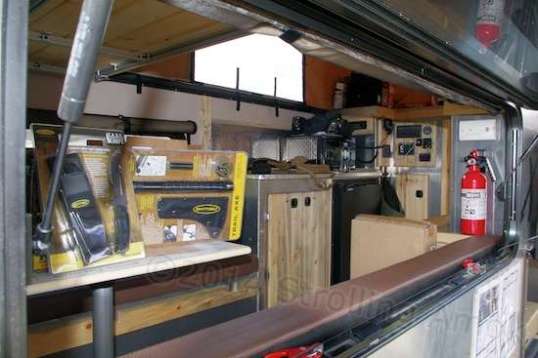 A shot through the open window shows the hint of long bench seats and dining table. That whole area flattens into a massive sleeping surface. A kitchen of sorts and pantry are further up.
