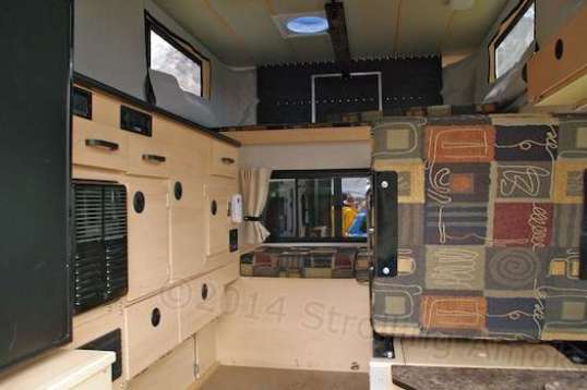 Driver's side of a Granby Side Dinette on display. Some of that cabinetry is occupied by appliances, propane bottles, and electronic controls.