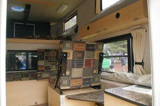 The right side of the Side Dinette shows the, ugh, side dinette, small table with space for a 2.5-gallon portable toilet underneath, and a vestigial storage cabinet at the rear. (The bed is forward and high.)