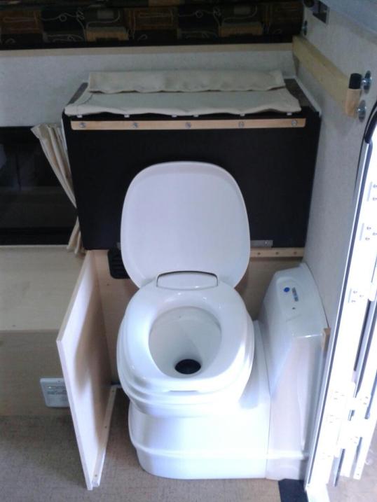Come on, I know y'all just love toilets, so here's what the cassette toilet option looks like. The bowl rotates at its base for getting it of the aisle, and is then shrouded over when not in use. Some people may wish to also close the entry door!