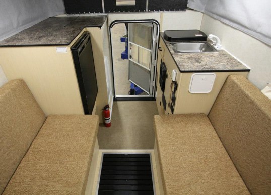 As shot from the bed area. This one has a max-sized fridge in trade for a storage tray above it, and a cassette toilet at left rear, in trade for less cabinet storage.