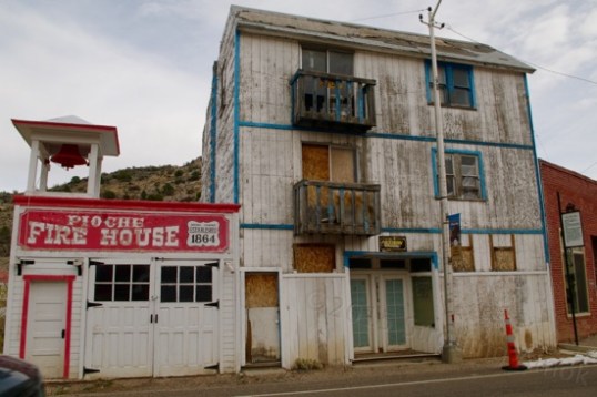 From the location of signage, the brick building on the extreme right was built in 1864-65 as the Pioche Commercial Club, a sort of social center. The wood building next to it was built in 1929 to house a fire truck acquired in 1928, and served for 25 years. It is now marked with defunct window signage for a dentist and a shoemaker. Best guess: the "fire house" was added later to house a second vehicle or equipment. Nearly all buildings in town swapped businesses and functions as the years progressed.