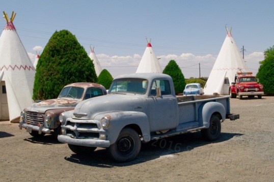 Chevy farm truck all but hides what I think is a Studebaker, with a GMC tow truck pulling up the rear - with a nearly modern light bar? And old Ford is at center rear.